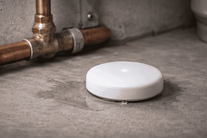 Smart water leak detector placed near basement pipes to prevent damage.